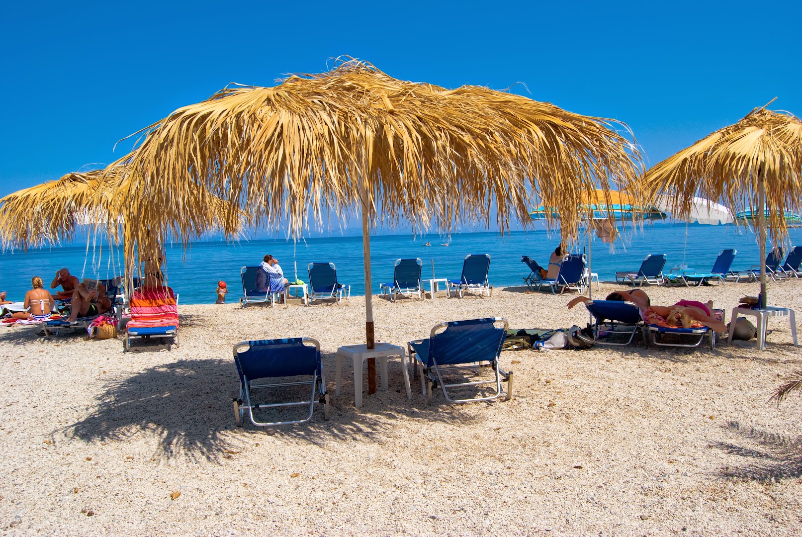 Viesnīcas Potamaki Beach pludmales zona ar daudziem sauļošanās krēsliem un saulessargiem saulainā dienā Korfu salā.