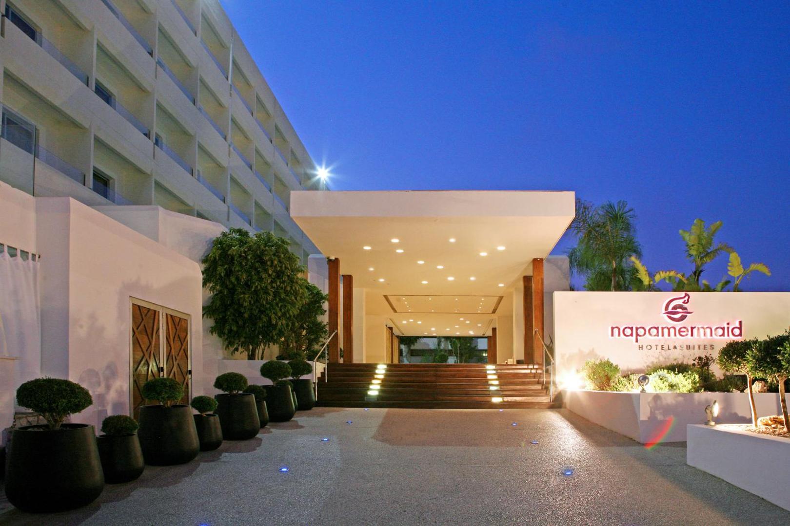 Napa Mermaid Hotel galvenā ieeja un fasāde nakts apgaismojumā Ajanapā — minimālisma stila arhitektūra un izgaismoti pakāpieni.