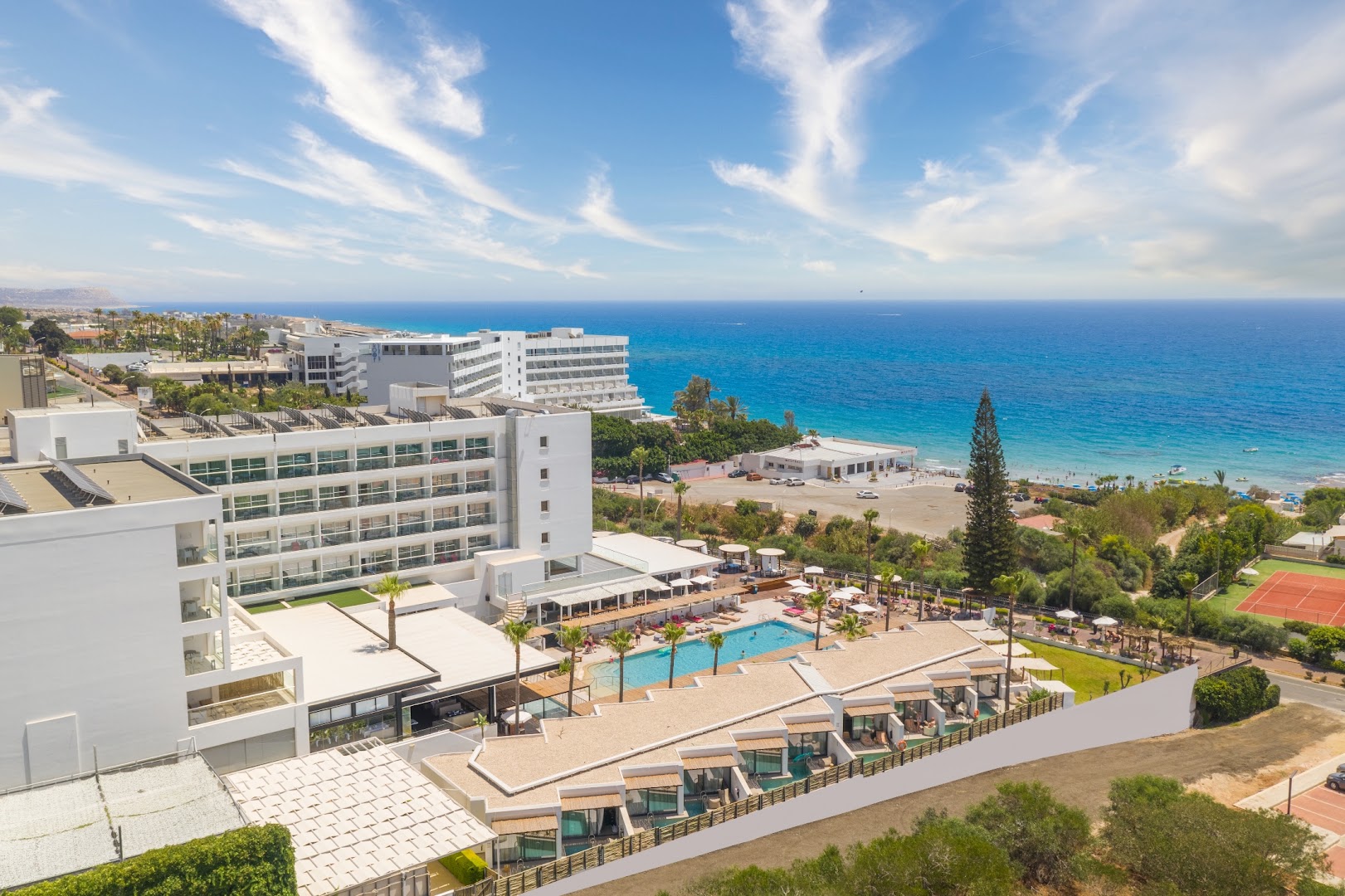 Napa Mermaid Hotel panorāmas skats Ajanapā — viesnīcas ēka, āra baseins un Vidusjūras piekraste ar zilu ūdeni un debesīm.