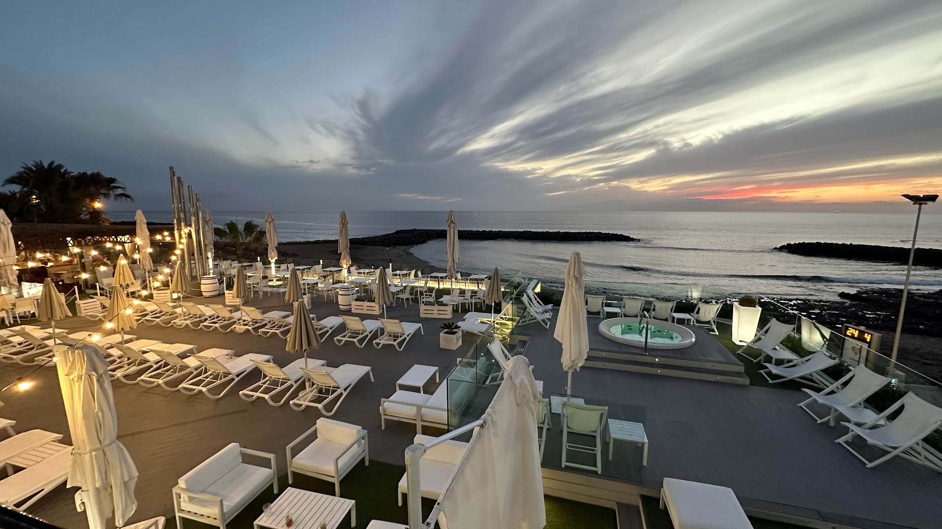 H10 Gran Tinerfe āra terase saulrietā ar sauļošanās krēsliem, džakuzi un dekoratīvām gaismām Tenerifes piekrastē