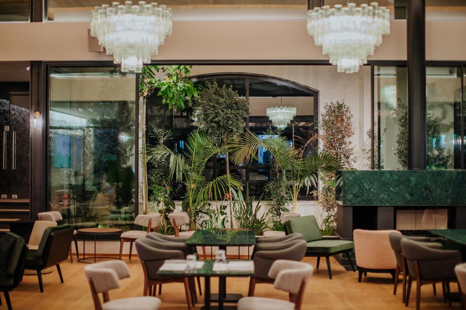 Napa Plaza viesnīcas iekštelpu atpūtas zona ar modernām mēbelēm, dizaina lustrām un zaļajiem augiem Aijanapā