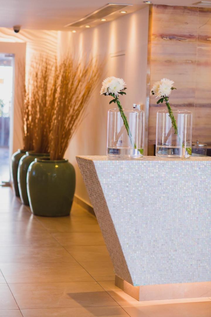 Napa Plaza viesnīcas spa centra recepcijas lete ar dekoratīviem ziediem un minimālistisku dizainu Kiprā