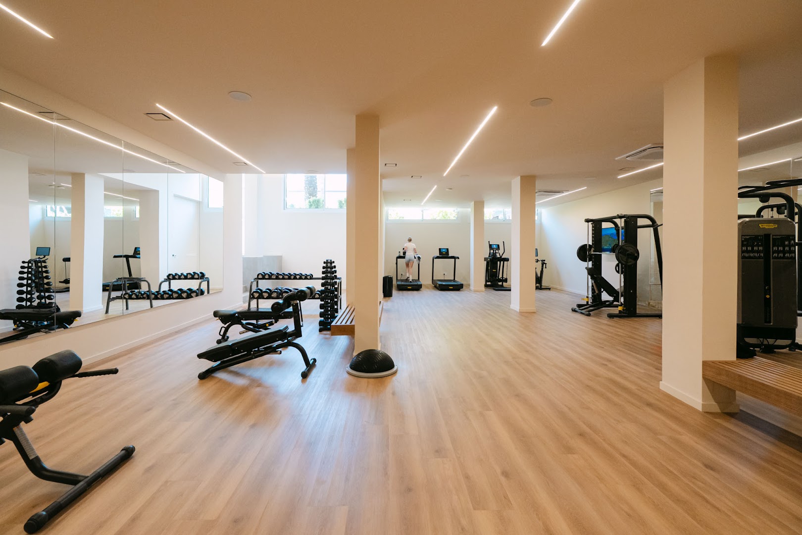 Napa Plaza viesnīcas plašais fitness centrs ar moderniem trenažieriem, brīvajiem svariem un spoguļu sienu gaišā telpā