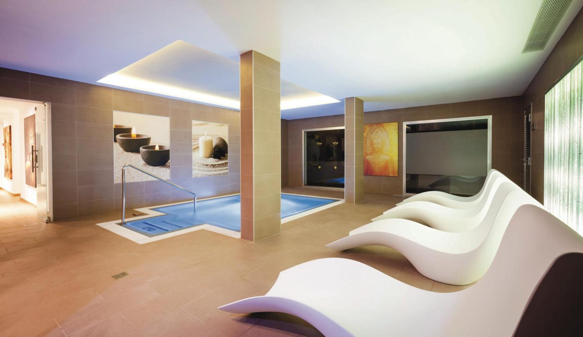 Riu Arecas Hotel spa zona ar iekštelpu baseinu un moderniem atpūtas krēsliem Tenerifē — relaksējoša atmosfēra ar sveču attēliem pie sienām