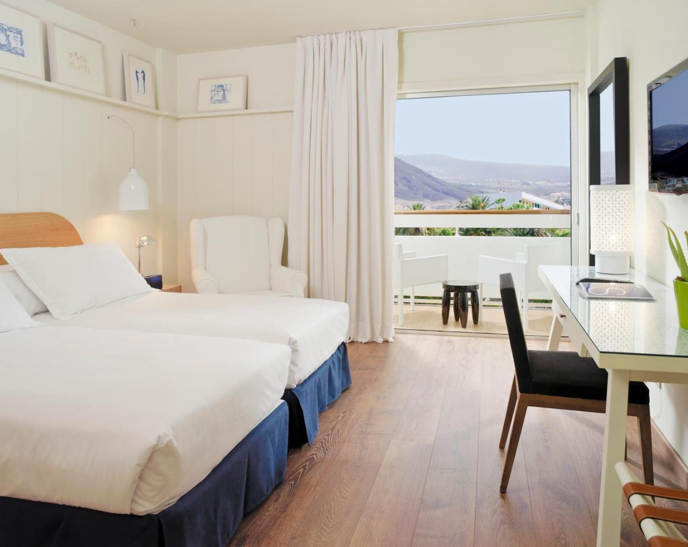 H10 Big Sur viesnīcas numura interjers ar divām gultām un balkonu, no kura paveras skats uz Tenerifes kalniem