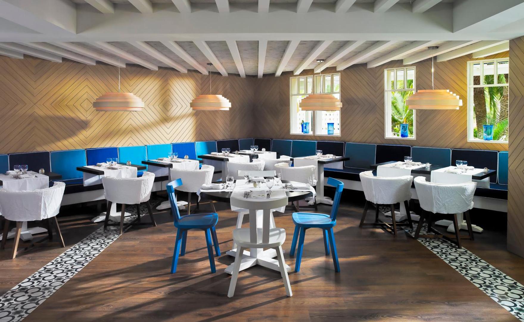Viesnīcas H10 Big Sur restorāns ar modernu dizainu, zilām mēbelēm un koka apdari Tenerifē — gaiša un mājīga ēdamzāle