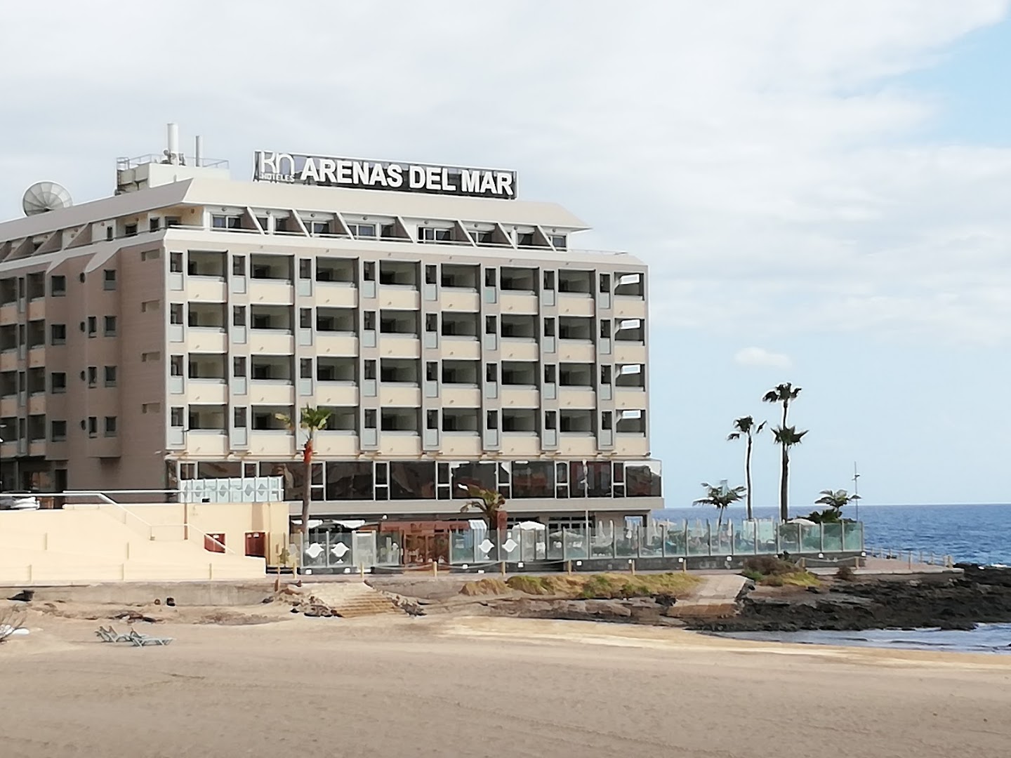 KN Arenas del Mar viesnīcas fasāde no pludmales puses — skats uz numuru balkoniem un smilšu joslu piekrastē