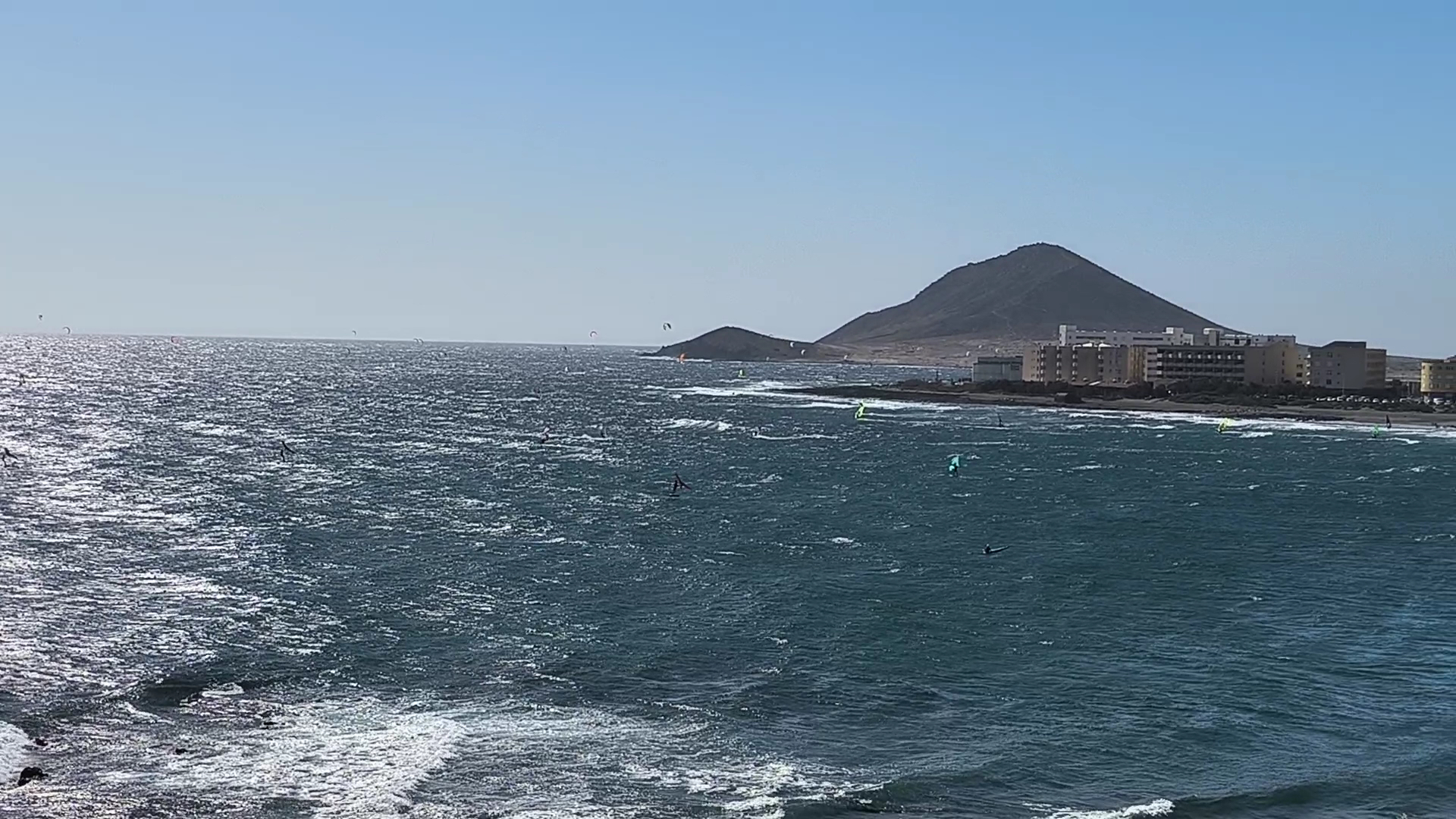 Skats uz Atlantijas okeānu un sērfotājiem pie KN Arenas del Mar viesnīcas El Medano kūrortā, Tenerifē