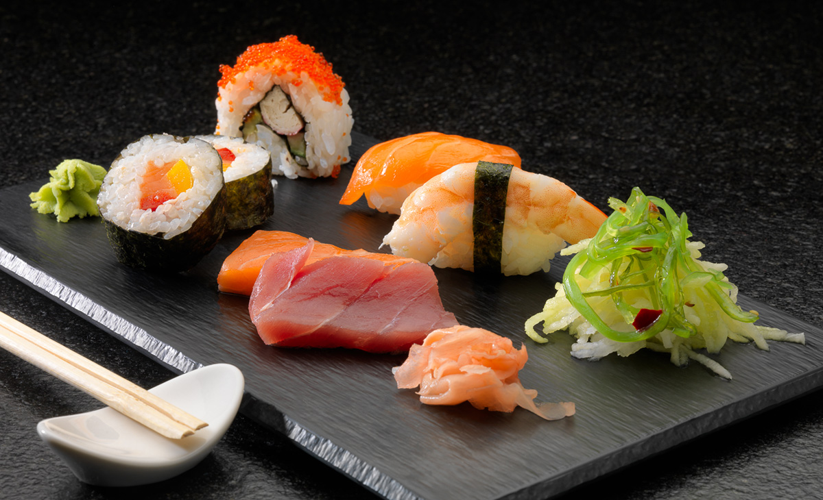 H10 Conquistador restorāna suši izlase uz melnas akmens paplātes ar nigiri, maki un jūras zāļu salātiem
