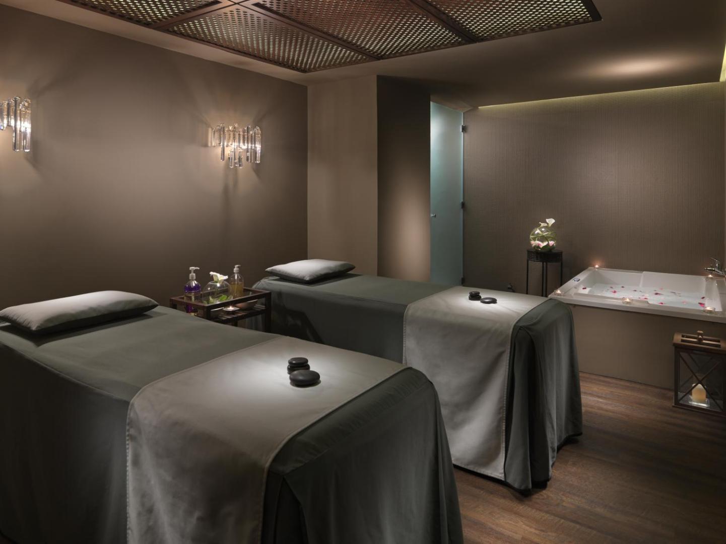 H10 Conquistador spa procedūru telpa ar divām masāžas gultām un burbuļvannu stūrī — relaksējošs apgaismojums un mierīga gaisotne