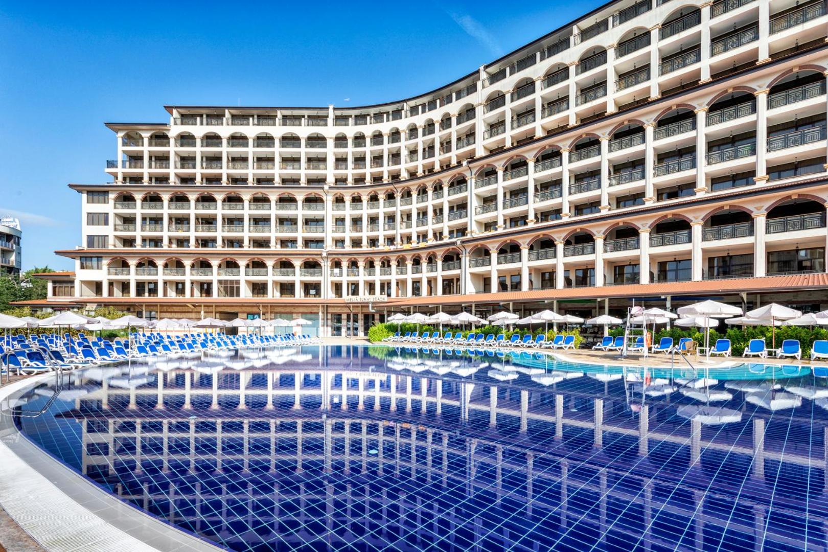 Melia Sunny Beach Resort modernā arhitektūra un numuru balkoni pie liela, zila baseina ar dzidru ūdens atspulgu