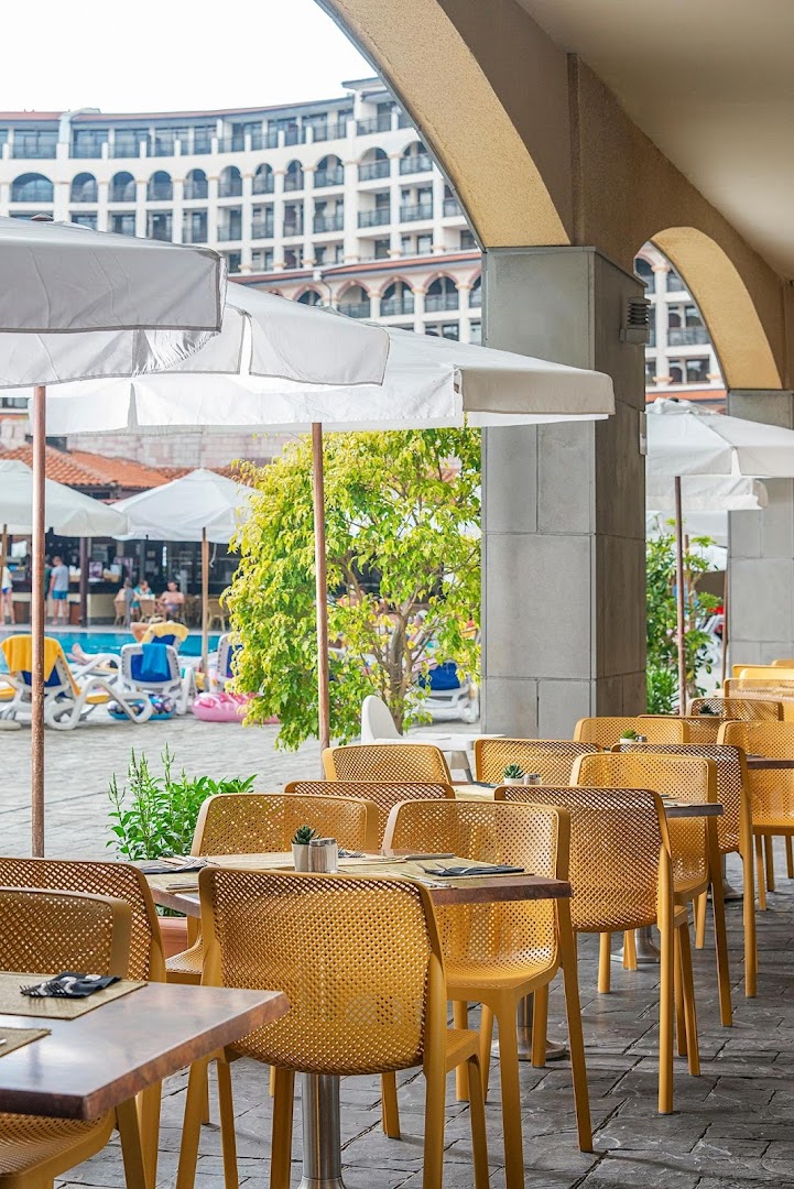 Melia Sunny Beach Resort āra kafejnīca zem arkām ar dzelteniem krēsliem un skatu uz baseina zonu un saulessargiem
