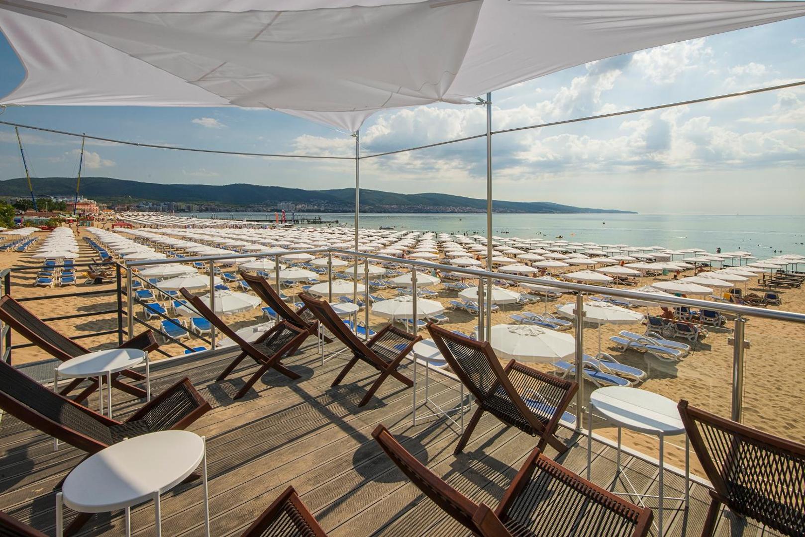 Skats no Melia Sunny Beach Resort pludmales terases uz plašo smilšu krastu ar simtiem baltu saulessargu un zilo jūru
