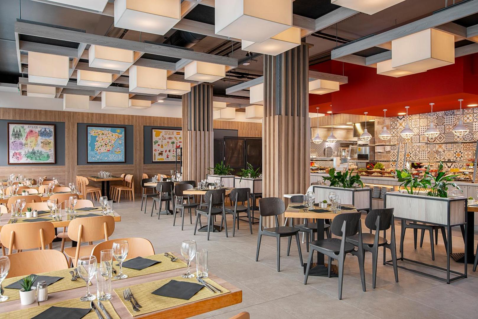 Melia Sunny Beach Resort modernais restorāns ar koka apdari un stilīgiem gaismas ķermeņiem — plaša ēdamzāle ar daudzveidīgu bufetes izvēli