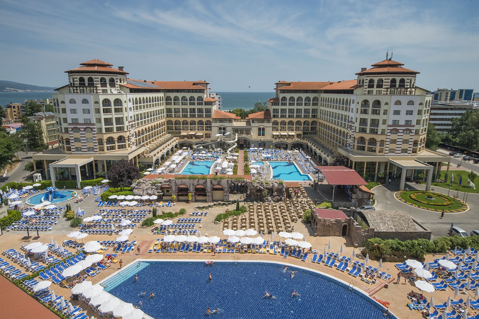 Melia Sunny Beach Resort plašais baseinu komplekss Bulgārijā ar sauļošanās krēsliem, saulessargiem un skatu uz Melno jūru saulainā dienā