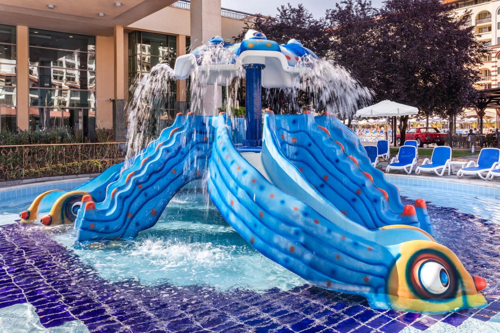 Melia Sunny Beach Resort bērnu baseins ar zilu slidkalniņu zivs formā un ūdens strūklakām saulainā dienā