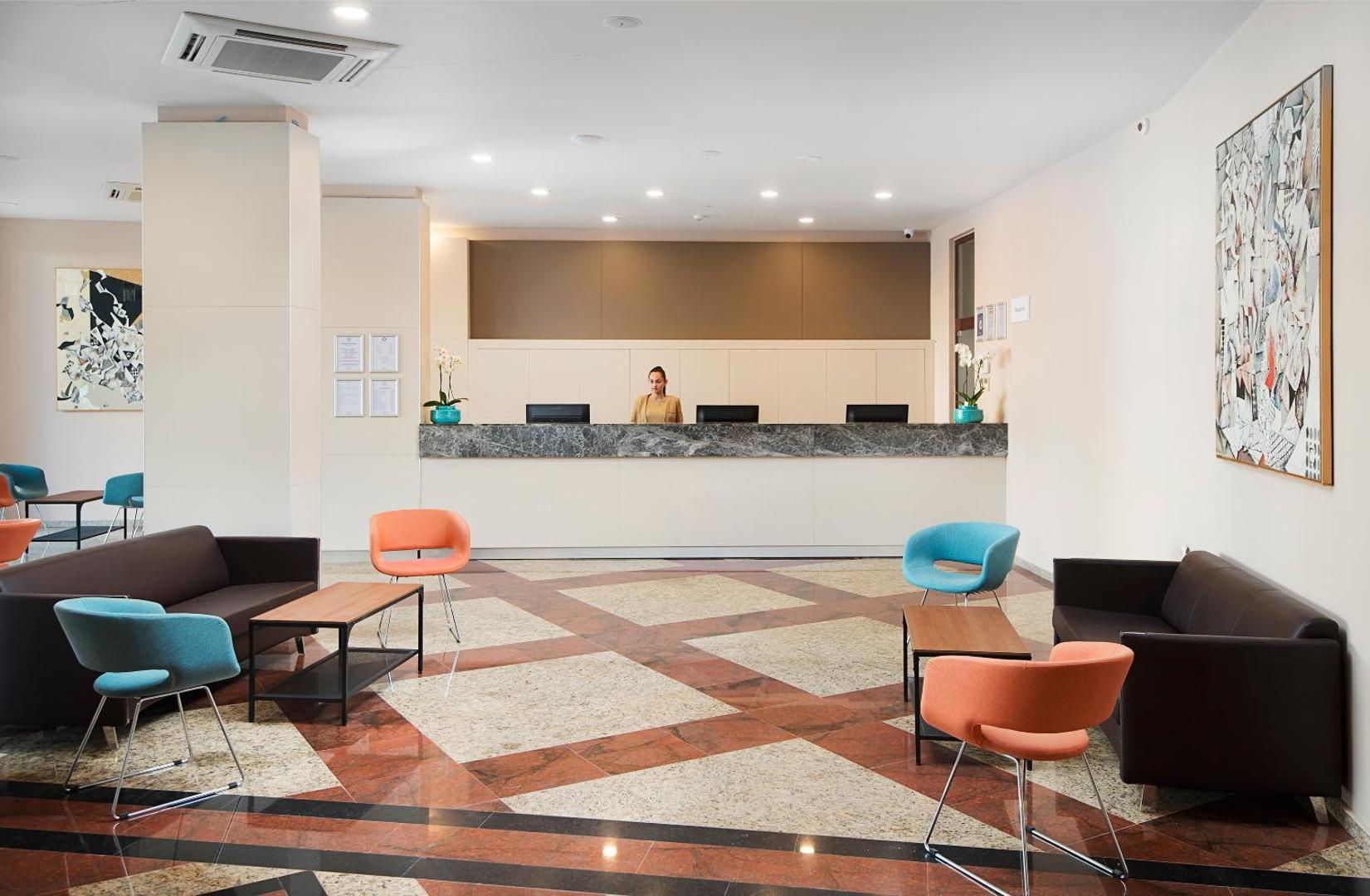 Viesnīcas Melia Sunny Beach Resort recepcijas lete ar personālu un atpūtas zonu, kurā izvietoti krāsaini atpūtas krēsli