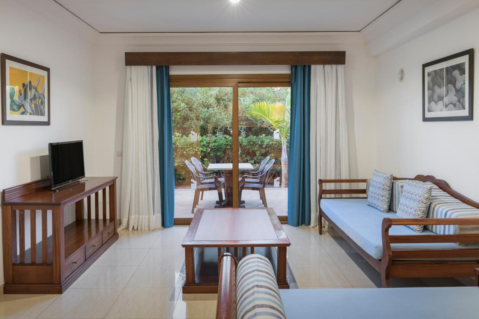 Marylanza Suites & Spa viesistabas zona ar dīvāniem, televizoru un izeju uz privātu terasi ar āra mēbelēm