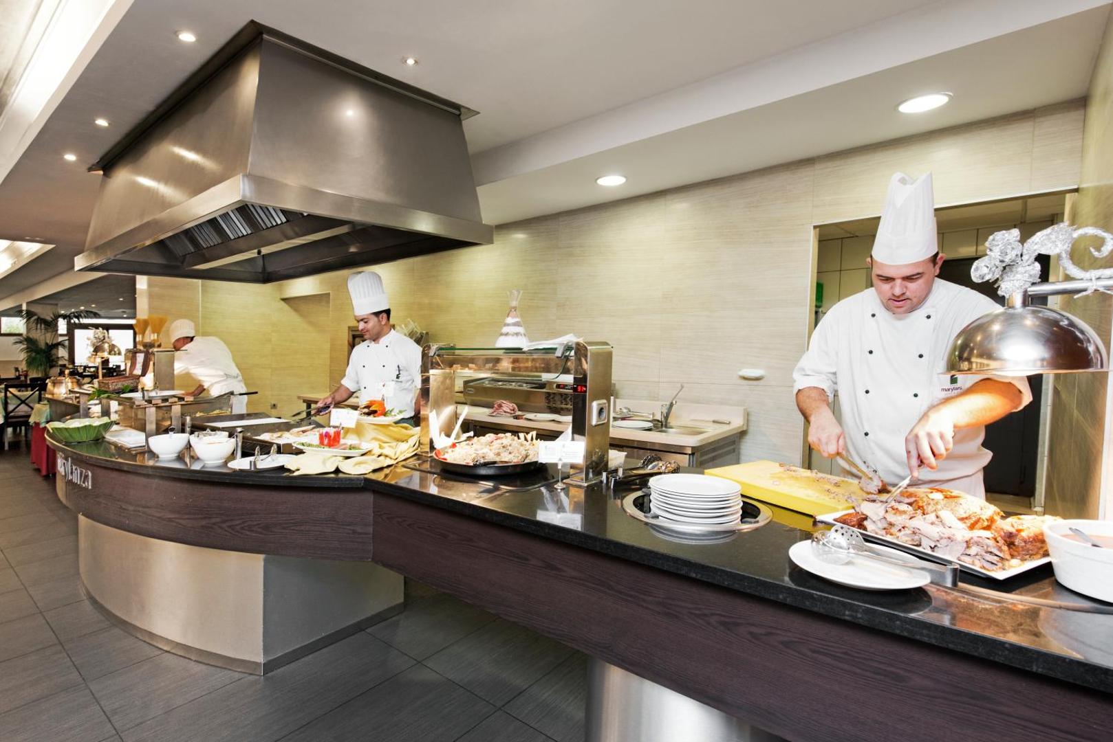 Marylanza Suites & Spa šefpavāri gatavo ēdienus atvērtā tipa virtuvē — bufetes restorāns ar plašu gaļas un uzkodu izvēli
