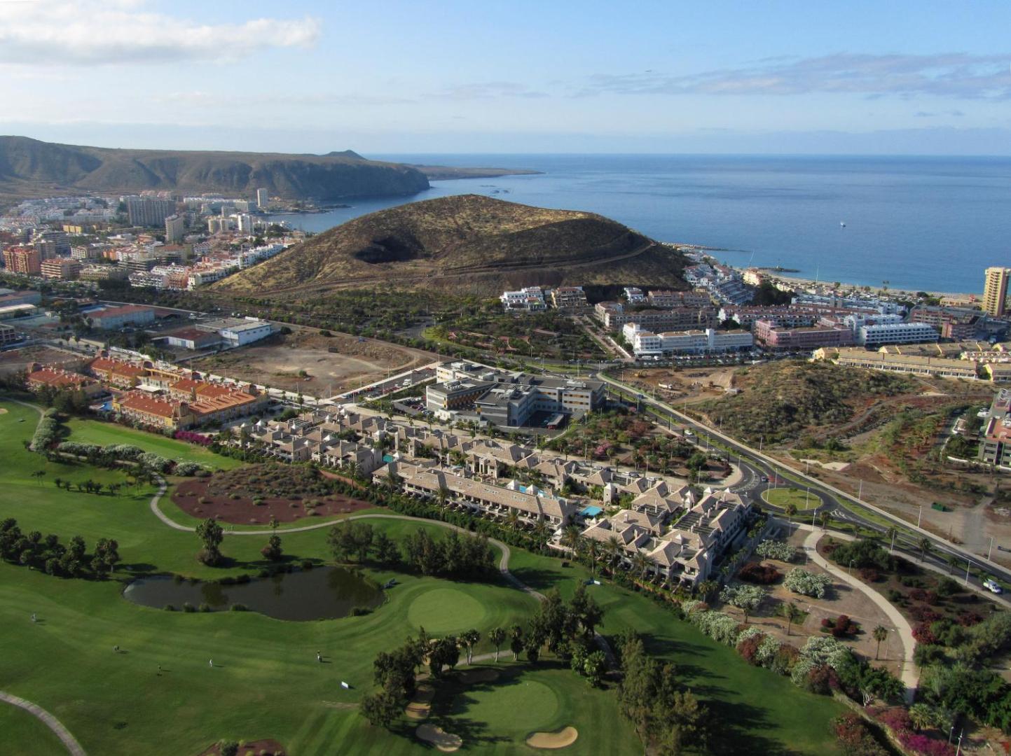 Marylanza Suites & Spa panorāmas skats no putna lidojuma uz golfa laukumiem, okeāna piekrasti un vulkānisko kalnu Tenerifes dienvidos