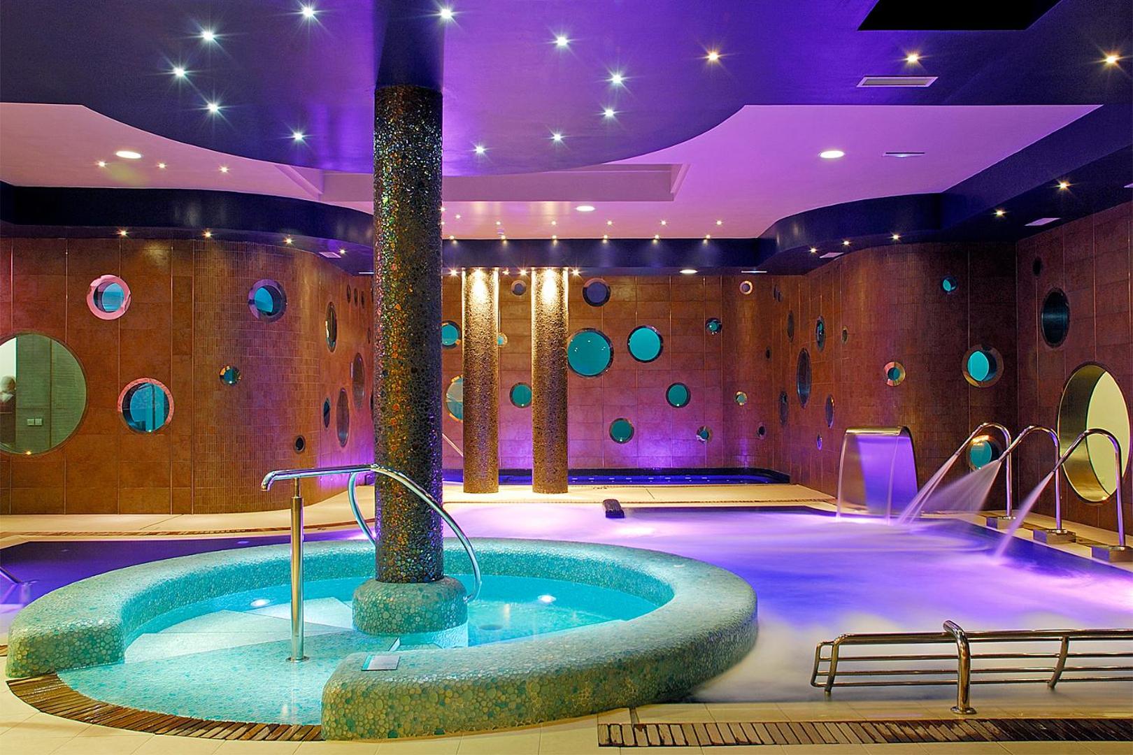 Marylanza Suites & Spa modernais spa centrs ar apsildāmu baseinu, kaskādēm un dekoratīvu apgaismojumu purpursarkanos toņos relaksācijai.