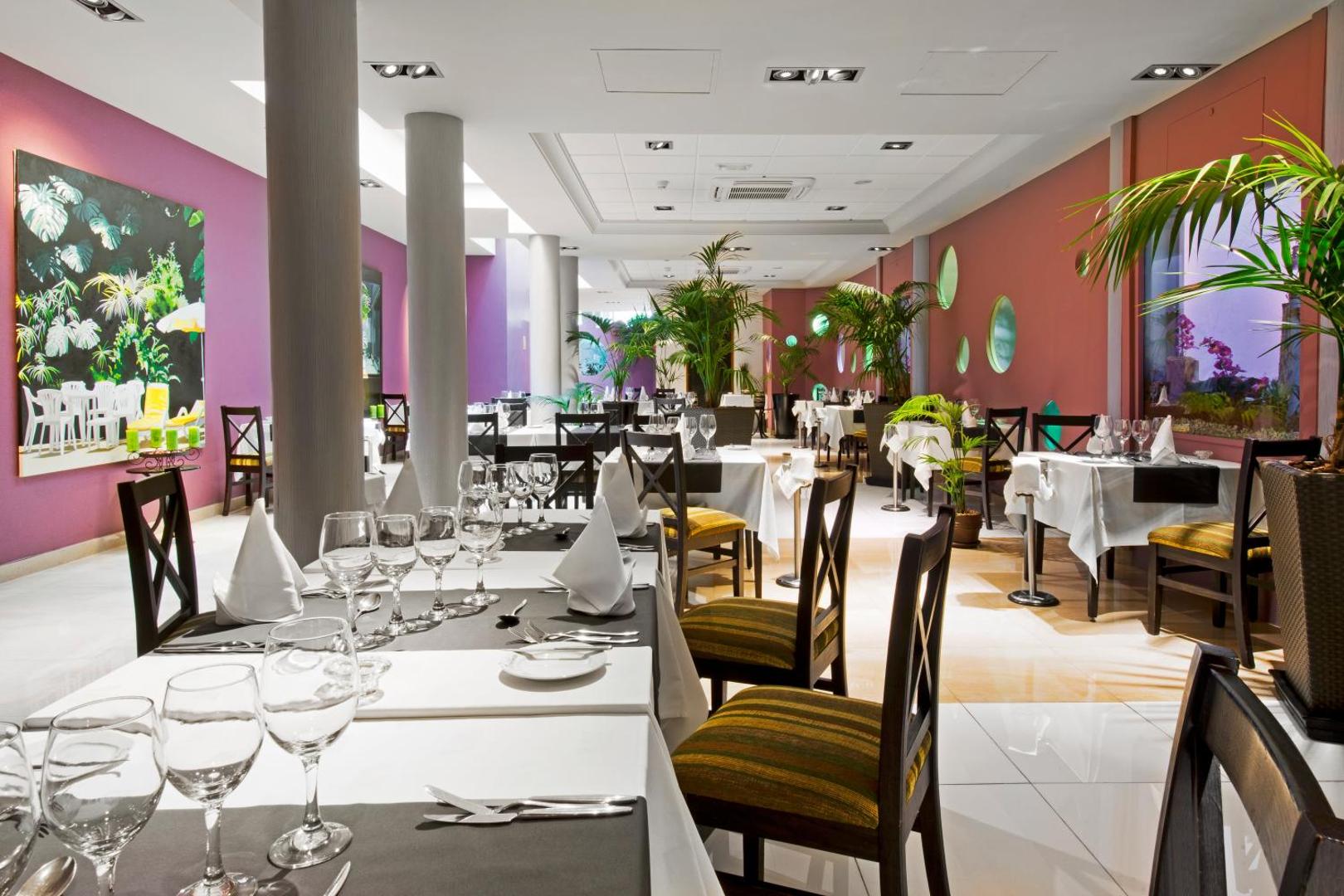 Marylanza Suites & Spa modernais restorāns ar eleganti klātiem galdiem, violetām sienām un dekoratīviem augiem iekštelpās