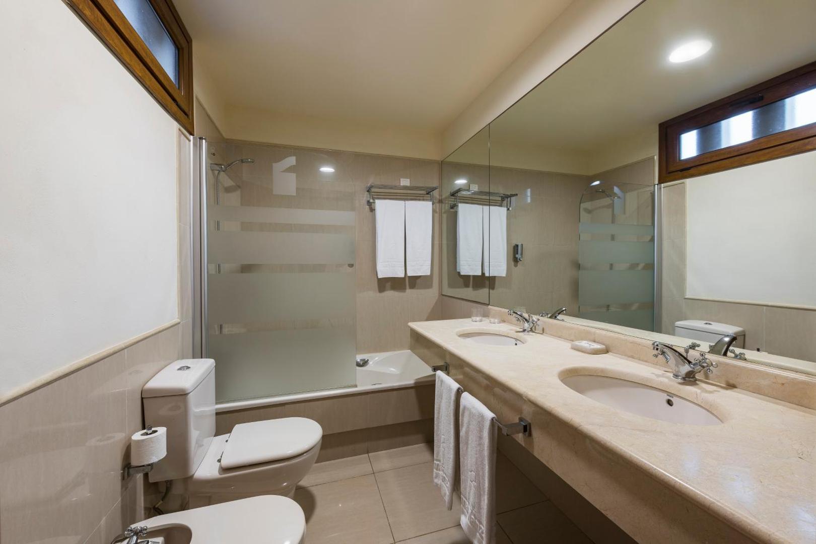 Marylanza Suites & Spa viesnīcas numura vannas istaba ar gaišu marmora virsmu, divām izlietnēm un vannu