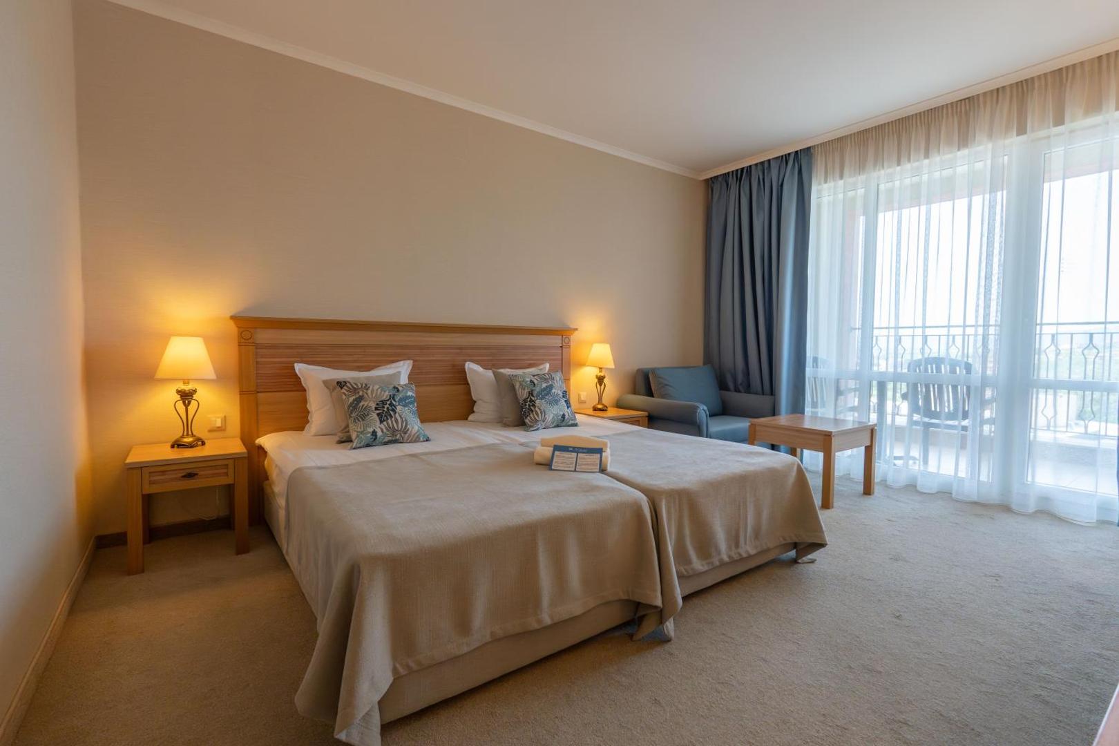 DIT Majestic Beach Resort gaišs divvietīgs numurs ar balkonu, mīkstajām mēbelēm un siltu apgaismojumu