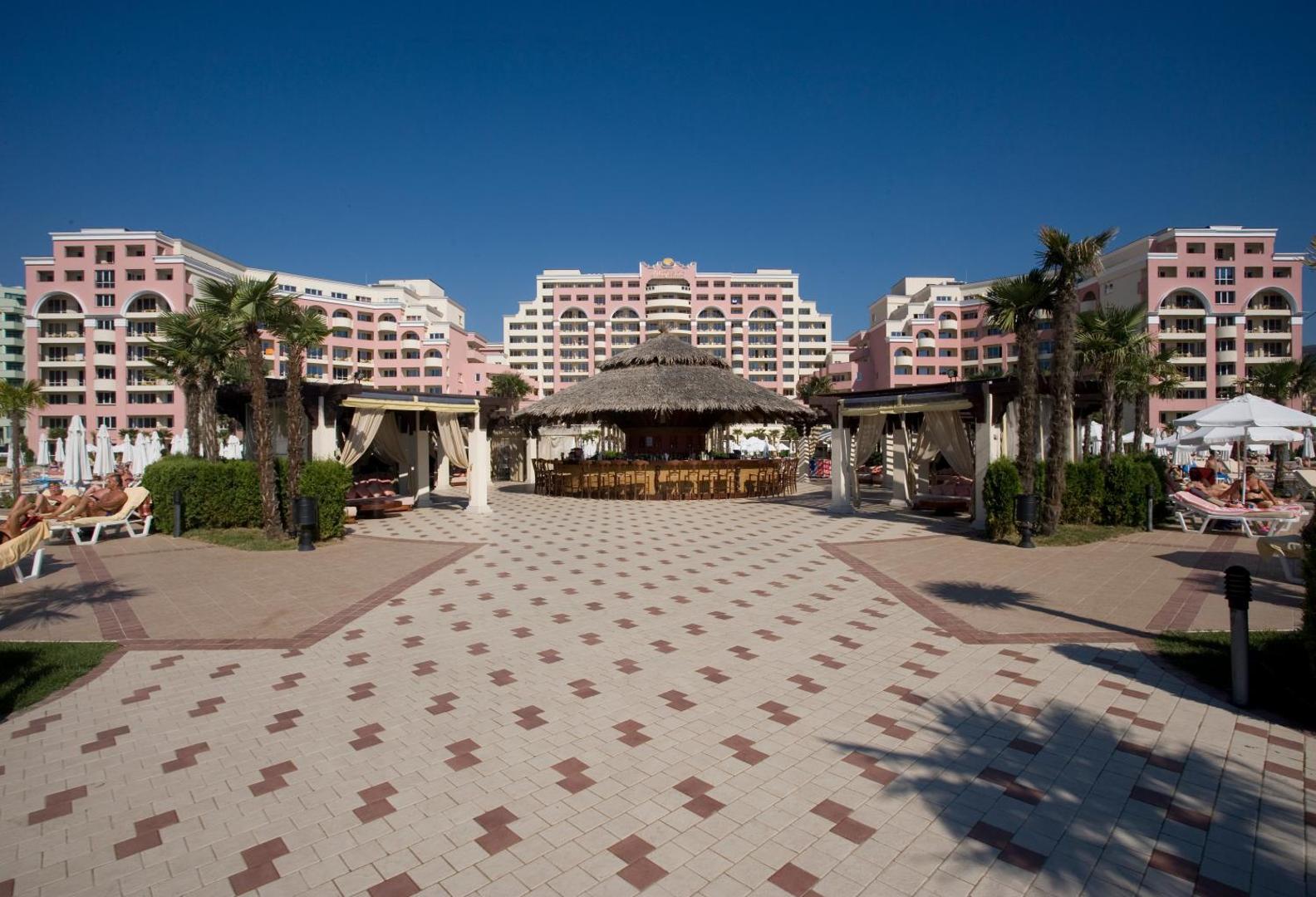 DIT Majestic Beach Resort āra bārs ar tropisku jumtu un atpūtas zonām pie baseina Saulainā krasta kūrortā