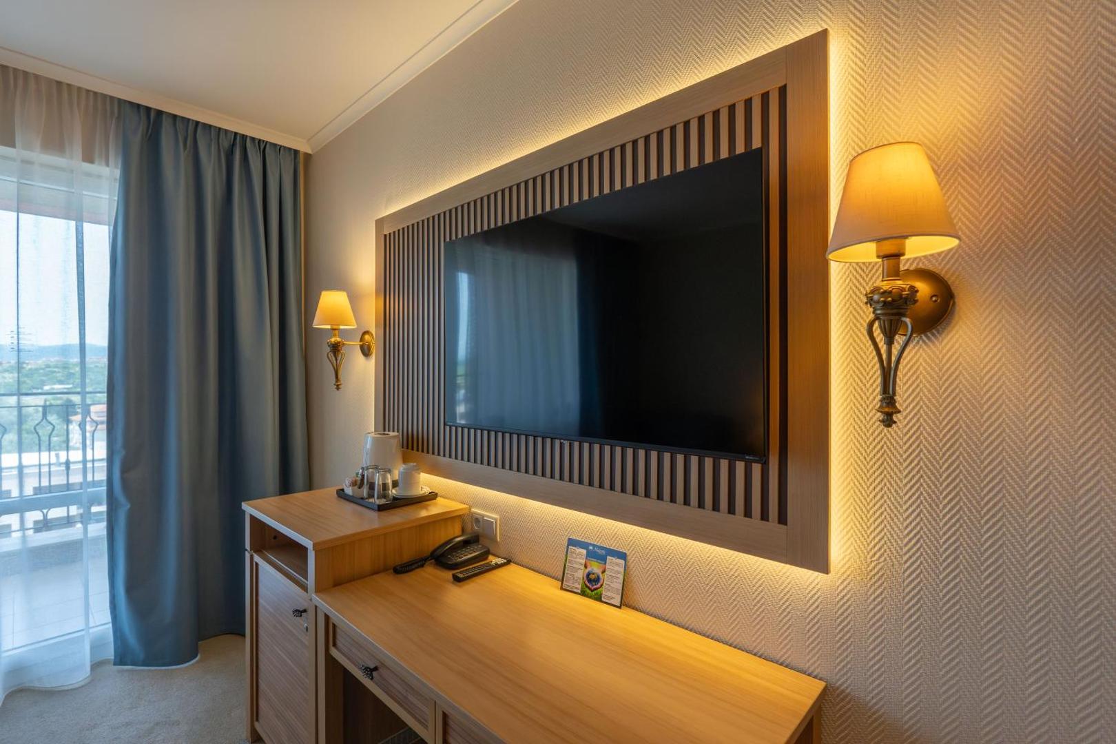DIT Majestic Beach Resort numura interjers ar sienas televizoru, darba galdu un dekoratīvu apgaismojumu