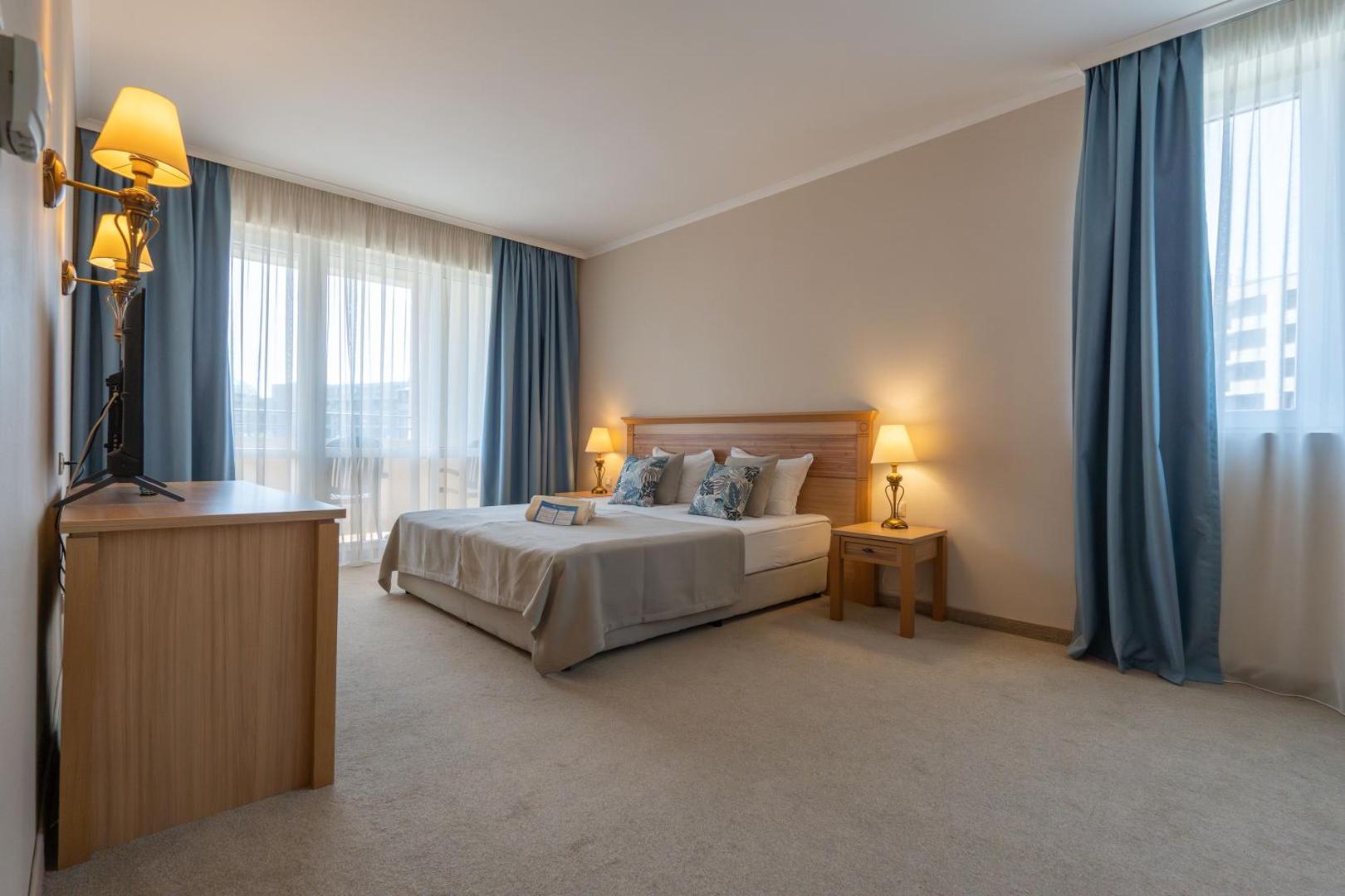DIT Majestic Beach Resort gaišs un plašs divvietīgais numurs ar lielu gultu, zilām aizkaru detaļām un izeju uz balkonu