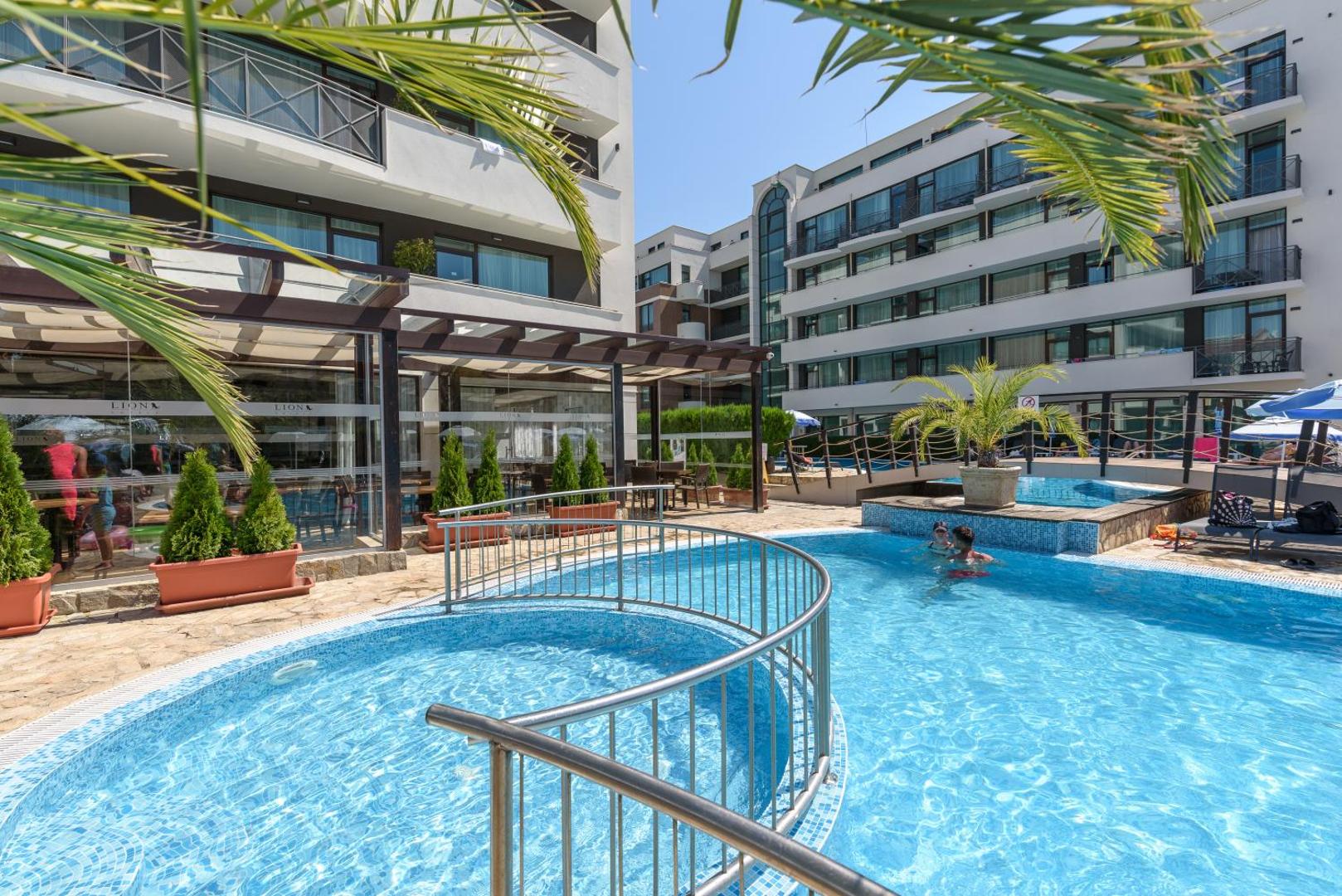 Lion Sunny Beach Hotel āra baseins ar bērnu zonu un metāla nožogojumu, blakus viesnīcas ēka un terase Saulainajā krastā, Bulgārijā