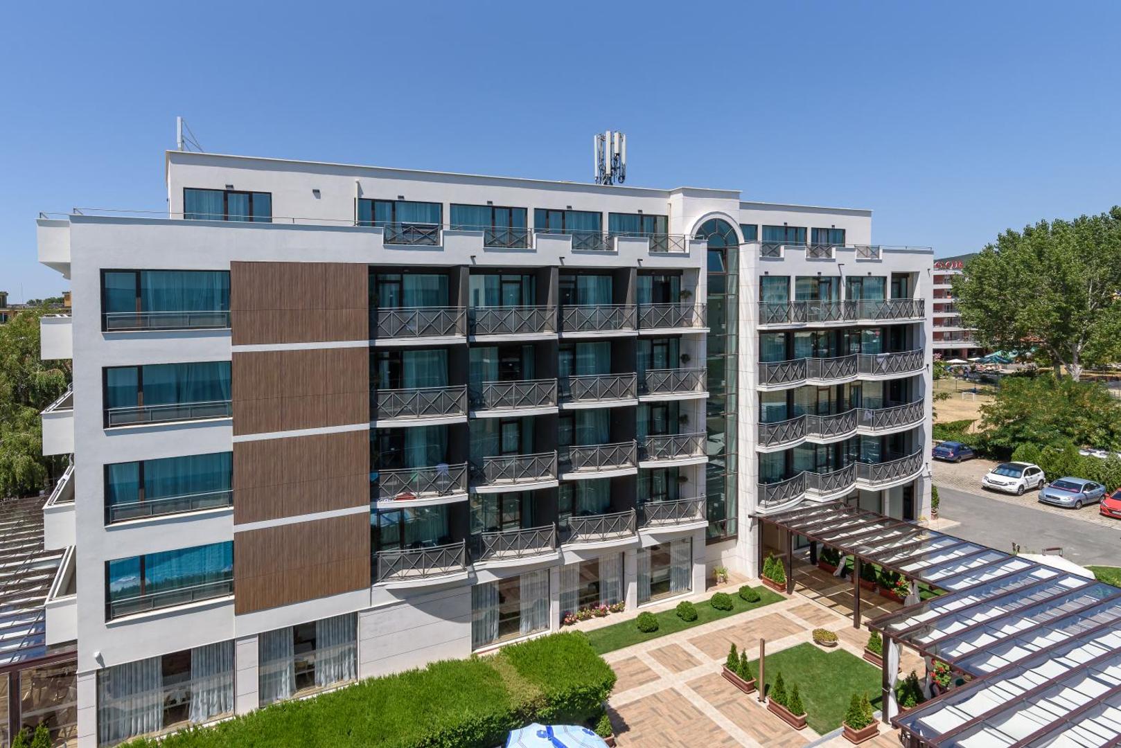 Lion Sunny Beach Hotel modernā fasāde ar balkoniem un labiekārtotu iekšpagalmu dienas laikā Bulgārijas kūrortā Saulainais Krasts