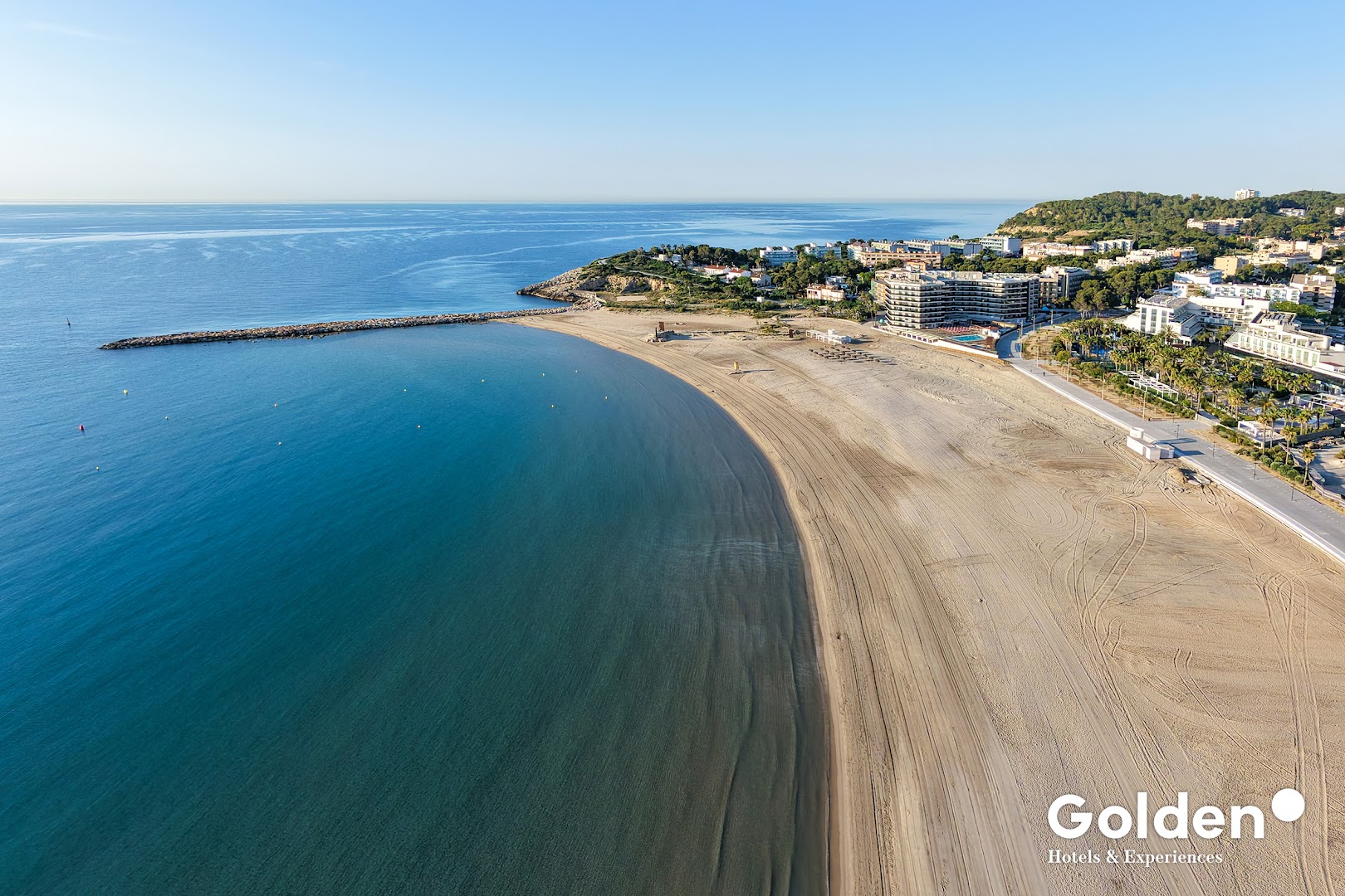 Golden Donaire Beach viesnīca un plašā smilšu pludmale Kosta Doradas piekrastē — skats no putna lidojuma uz Vidusjūras līci