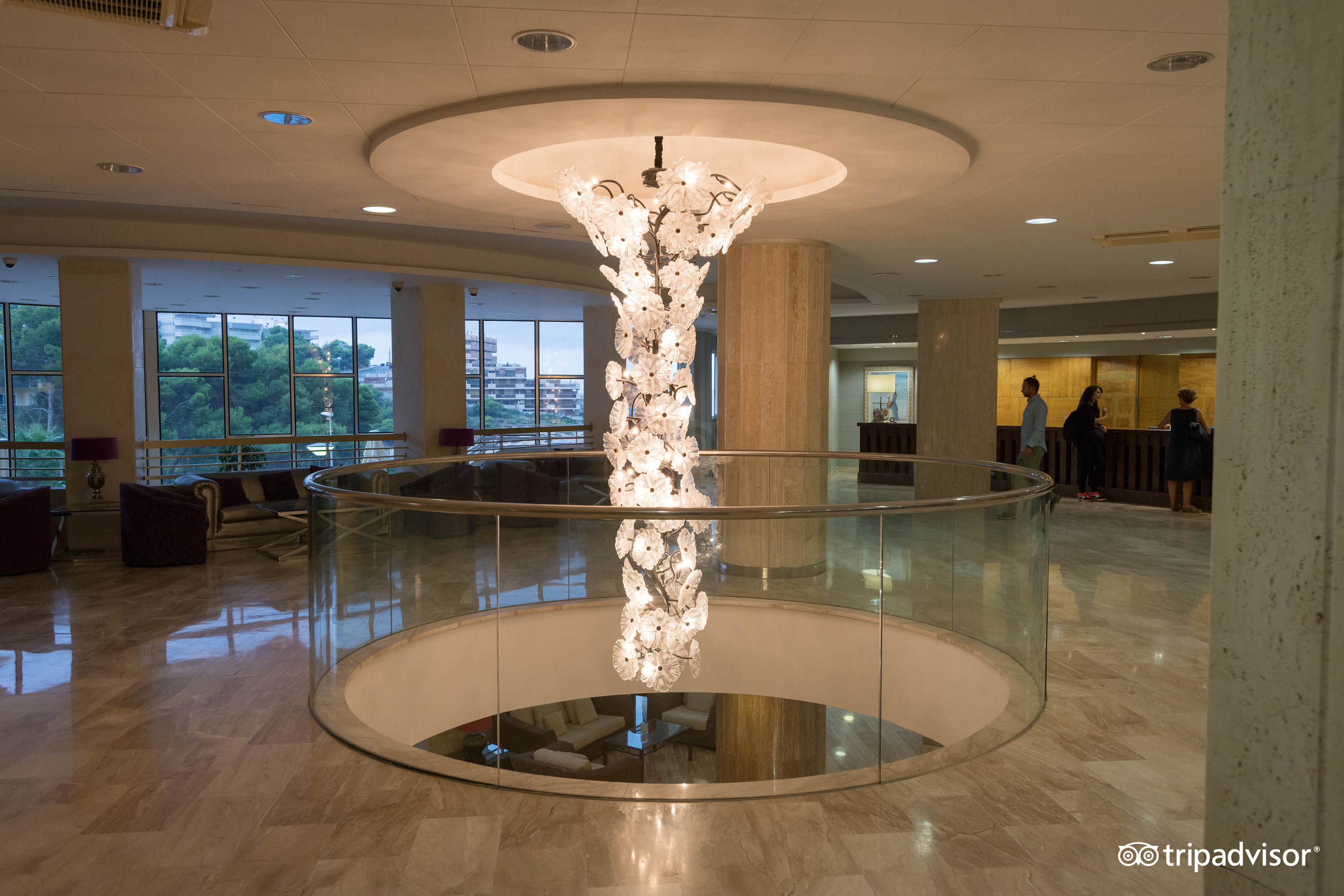 Hotel Cala Font centrālais vestibils ar iespaidīgu ziedu formas lustru un skatu uz apkārtnes zaļumiem