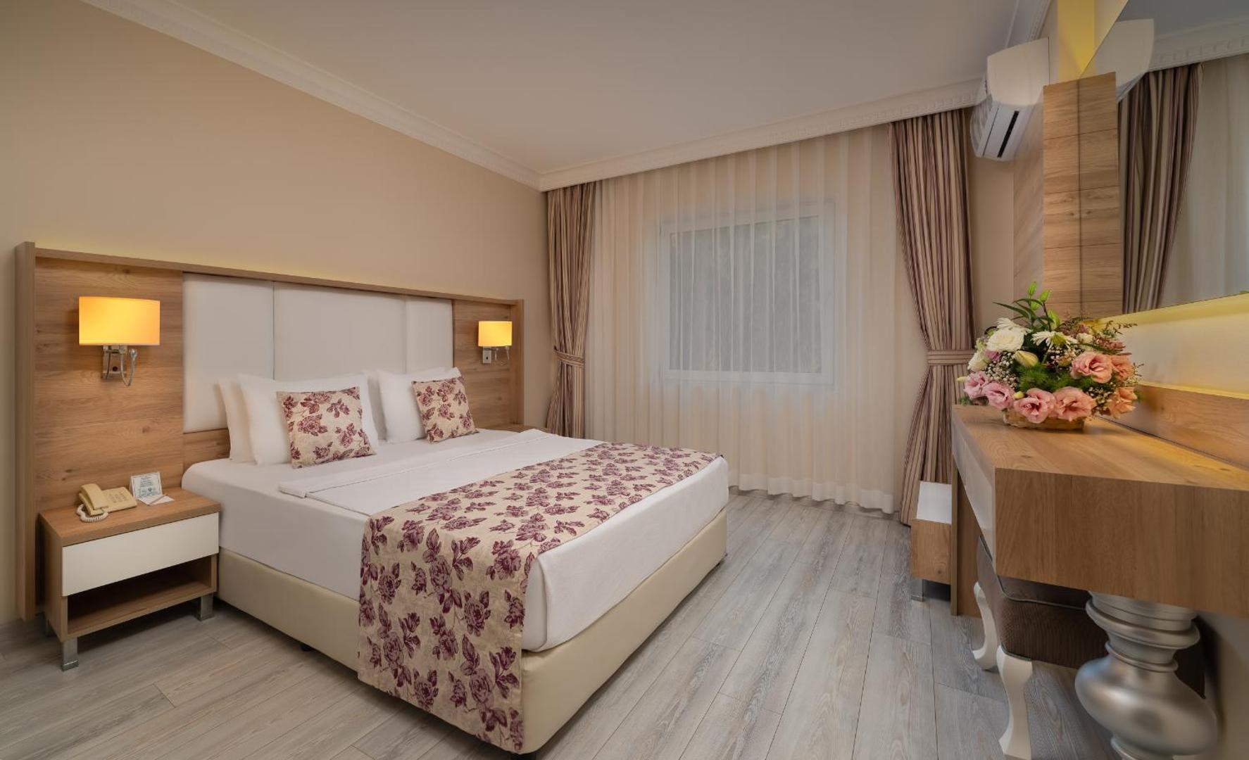 The Garden Beach Hotel numurs ar gaišu koka grīdu, ziedu motīviem tekstilā un dekoratīvu galdiņu