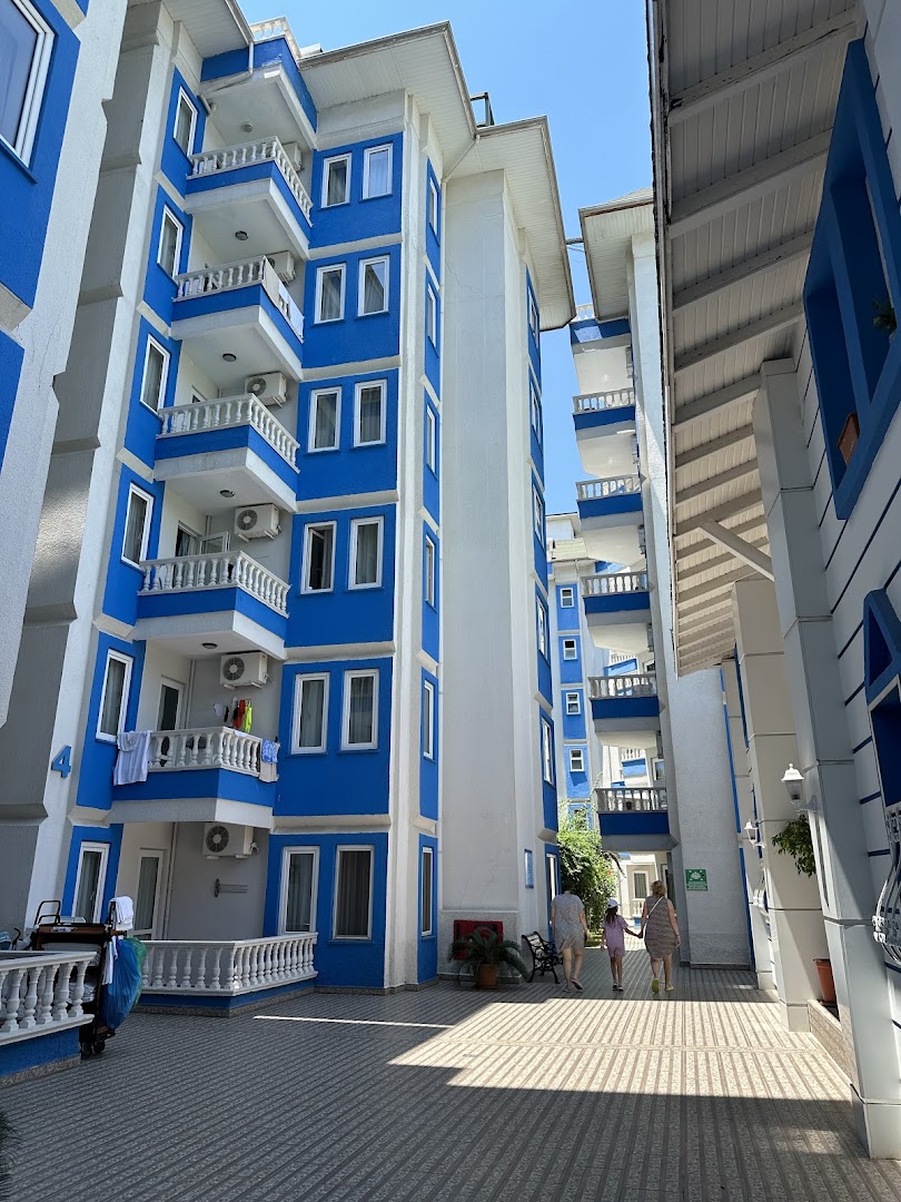 The Garden Beach Hotel zilbaltie korpusi ar balkoniem un iekšpagalmu, kur redzami viesi dodamies uz pludmali vai baseinu