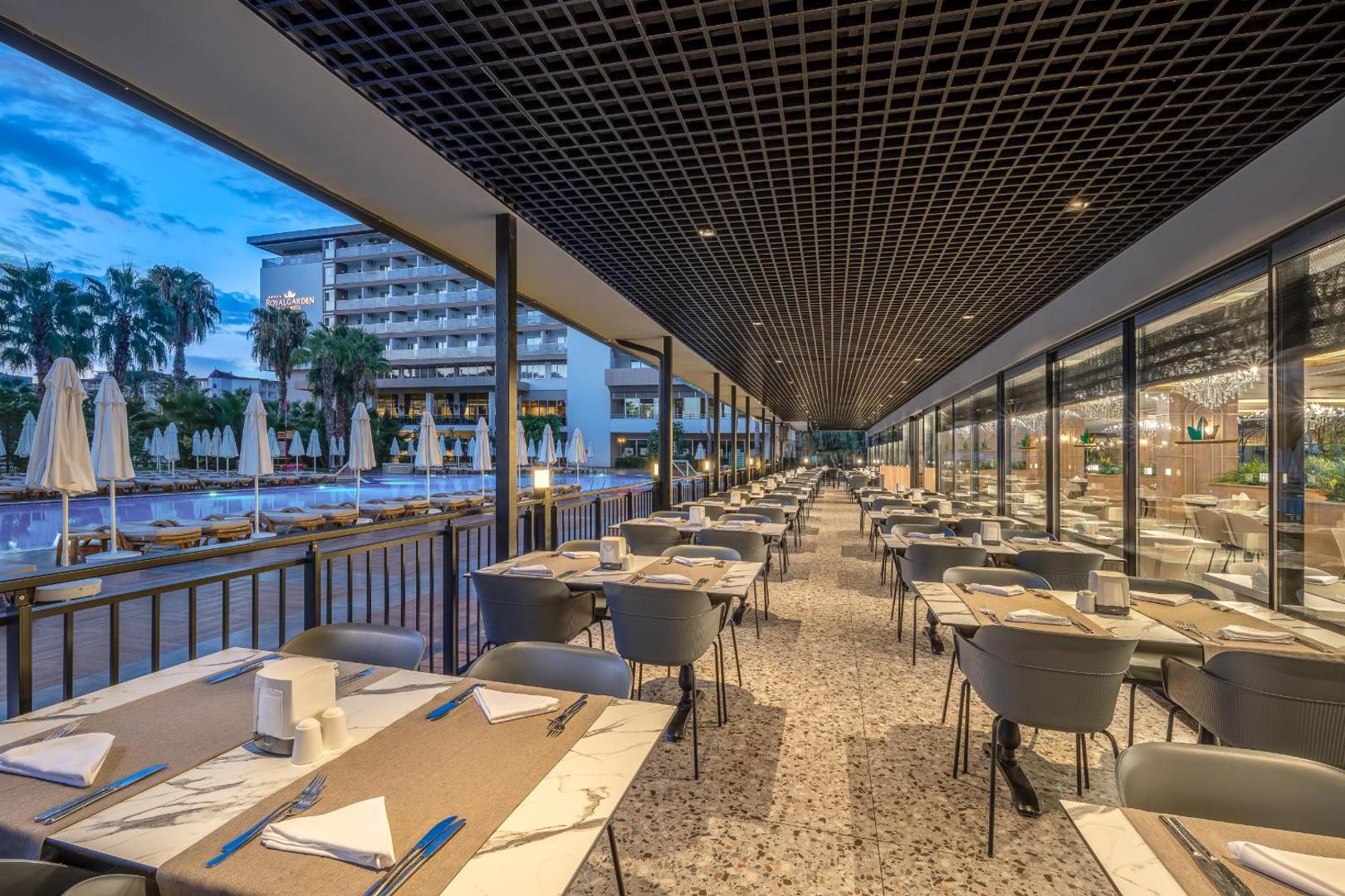 The Garden Beach Hotel āra terases restorāns ar skatu uz baseinu — eleganti klāti galdi vakariņām Alānijas kūrortā