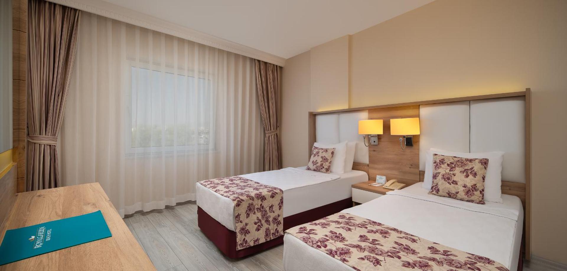 The Garden Beach Hotel gaišs numurs ar divām atsevišķām gultām, koka mēbelēm un mīkstu apgaismojumu mājīgai atpūtai