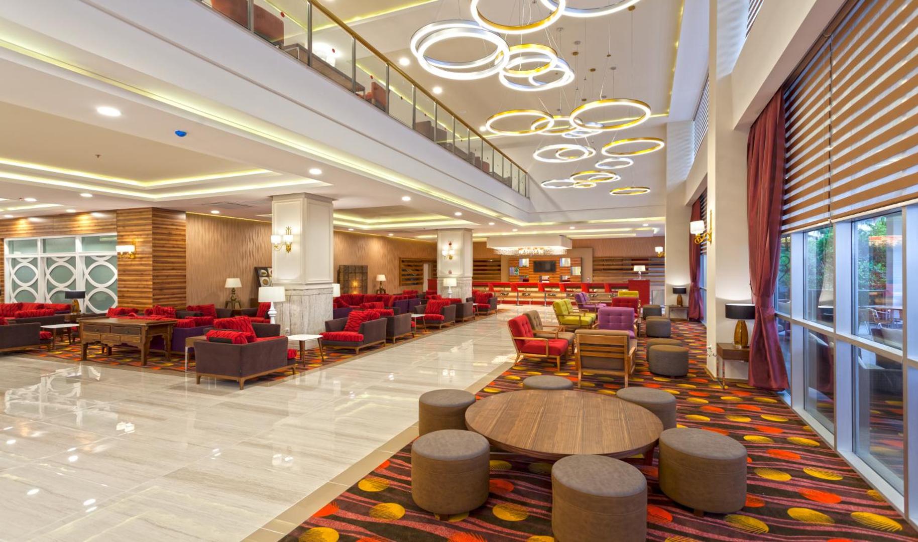 The Garden Beach Hotel plašais vestibils ar modernām mēbelēm, košiem paklājiem un dizaina gaismekļiem Alanjas reģionā, Turcijā