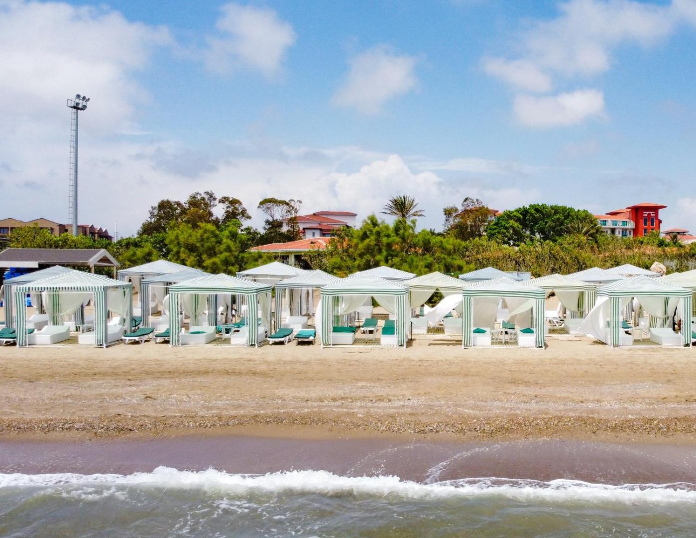 Grezni balti pludmales paviljoni Belconti Resort Hotel piekrastē — privātas atpūtas zonas ar mīkstiem zviļņiem pašā jūras malā