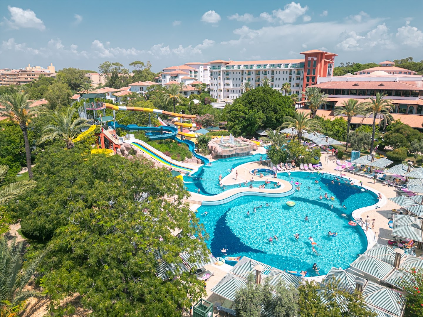 Belconti Resort Hotel plašais āra baseinu komplekss ar ūdens slidkalniņiem un palmu dārzu Belekā, Turcijā — skats no augšas