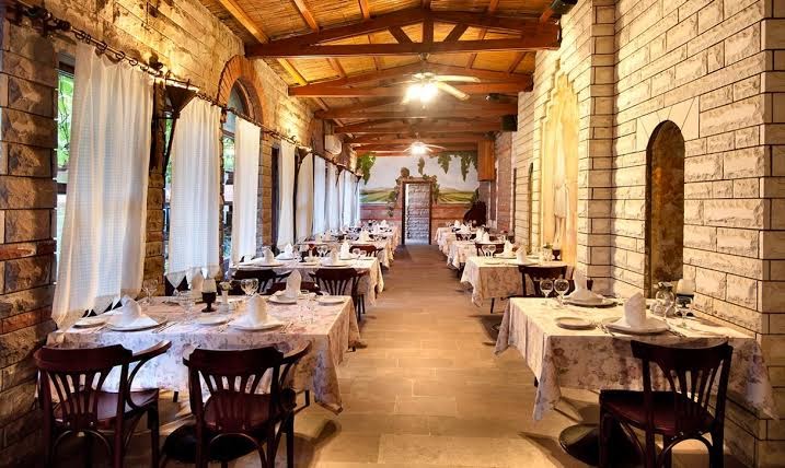Belconti Resort Hotel a la carte restorāns ar mūra sienām un koka griestiem — eleganti klāti galdi mājīgā, tradicionālā stilā