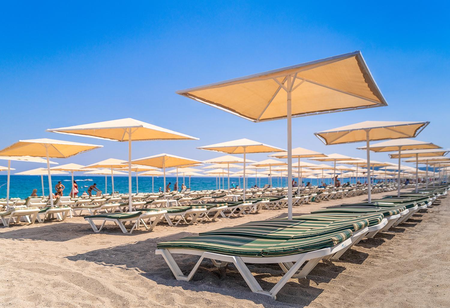 L'oceanica Beach Resort Hotel pludmales zona ar daudziem saulessargiem un sauļošanās krēsliem pie Vidusjūras Kemerā
