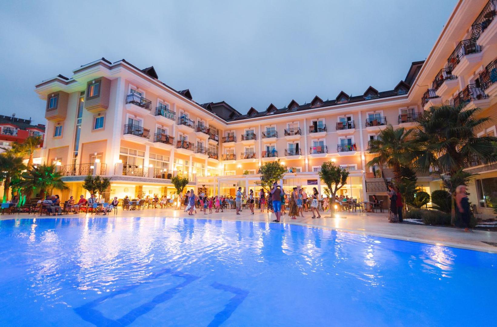 L'oceanica Beach Resort Hotel vakara pasākums pie izgaismota baseina ar viesiem, kuri dejo un bauda vakariņas pie galdiņiem.