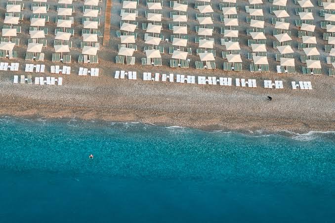 Aerofoto uzņēmums ar L'oceanica Beach Resort Hotel pludmales saulessargu rindām un dzidri zilo jūras ūdeni