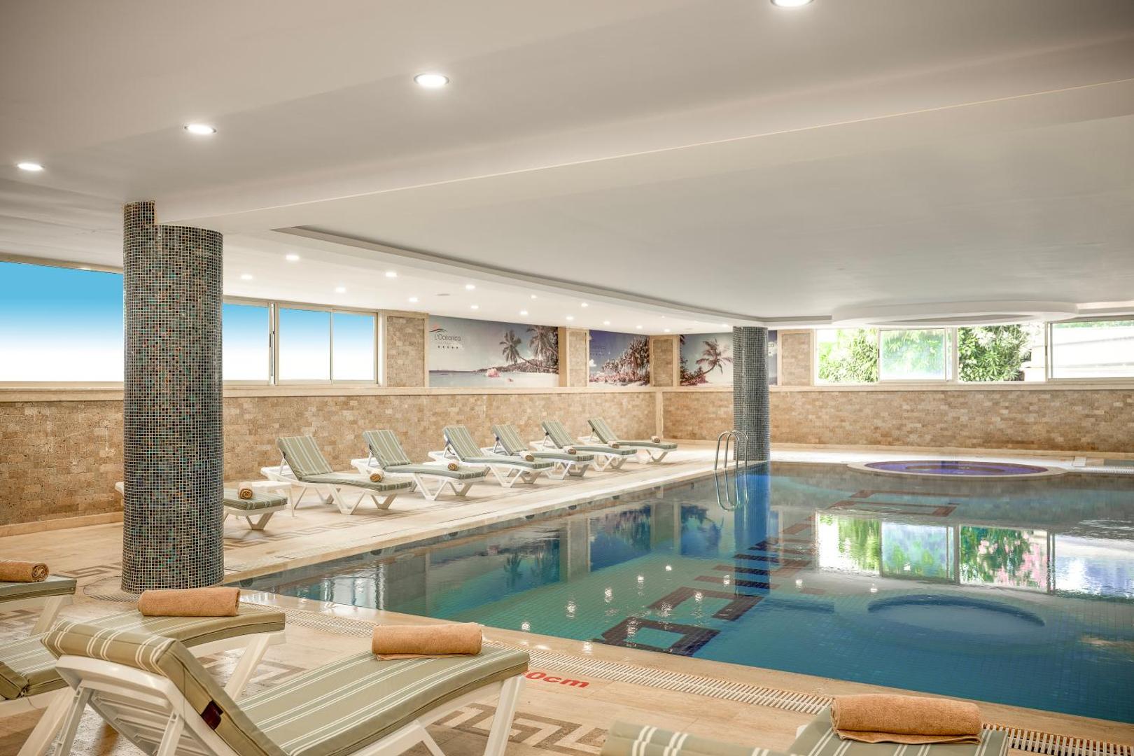 L'oceanica Beach Resort Hotel iekštelpu baseins ar apsildi, džakuzi zonu un ērtiem atpūtas krēsliem spa centrā.