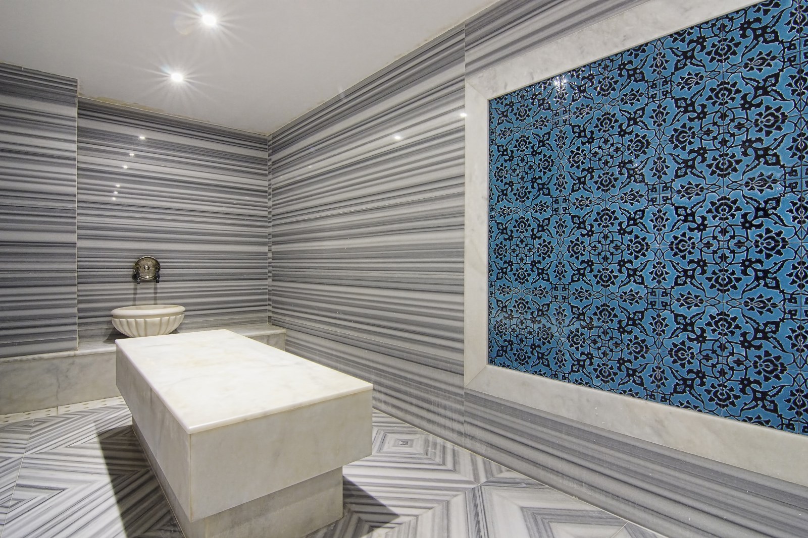 Tradicionāls turku hamams Rai Premium Tekirova spa centrā ar marmora apdari un zilu ornamentu flīzēm — relaksācijas zona