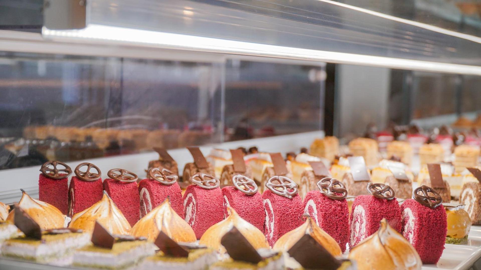 Tuvplāns ar smalkiem desertiem un kūkām Rai Premium Tekirova viesnīcas restorānā — koši sarkani biskvīta rullīši un bezē kūciņas
