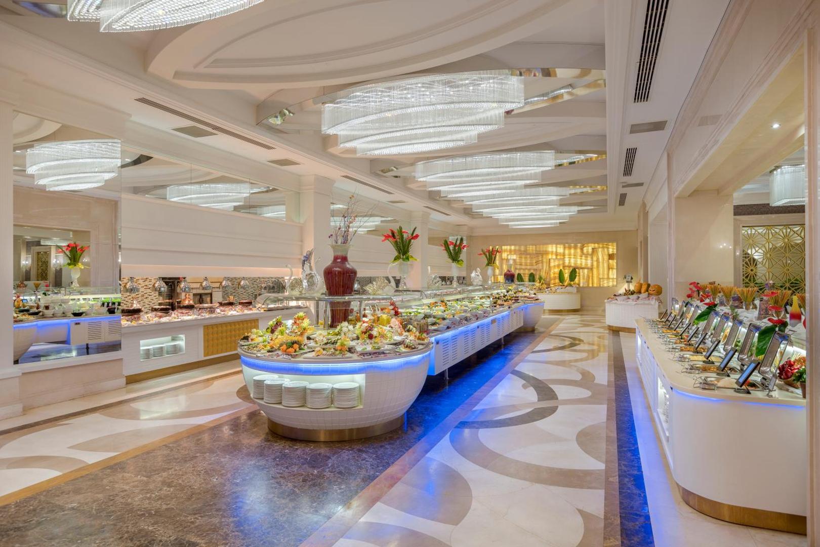 Dobedan Exclusive Hotel & Spa galvenais restorāns ar bagātīgu bufetes līniju, augļu kompozīcijām un greznām lustrām gaišā interjerā